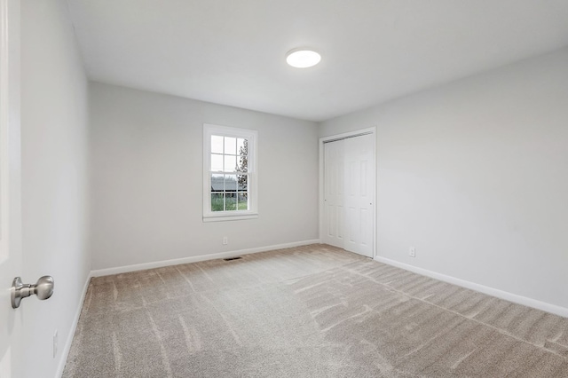 unfurnished room with light carpet, visible vents, and baseboards