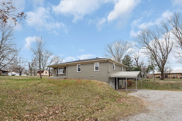 view of side of home with a carport, a yard, brick siding, and gravel driveway