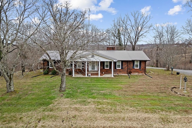 view of front facade with a front yard, brick siding, metal roof, and a chimney