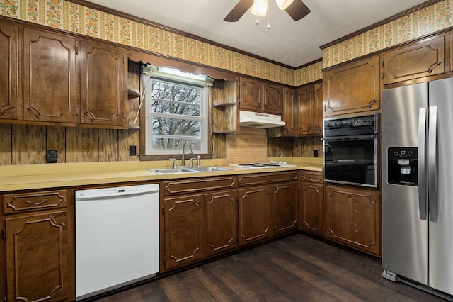 kitchen with white appliances, a sink, light countertops, dark wood-style floors, and wallpapered walls