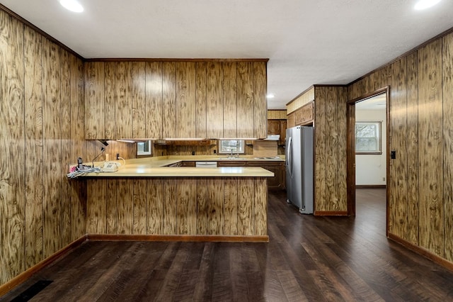 kitchen featuring dark wood-type flooring, freestanding refrigerator, light countertops, and a peninsula