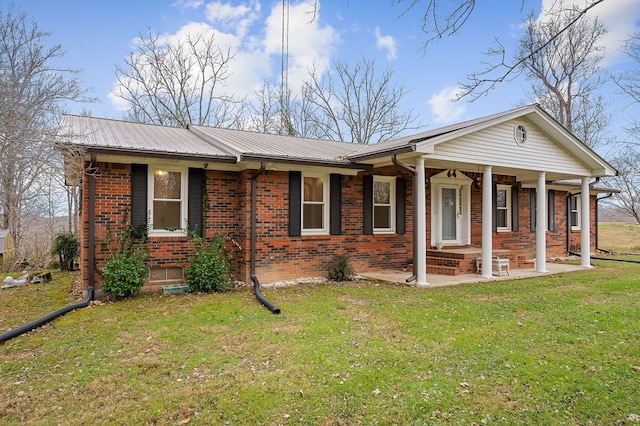 view of front facade with a porch, a front yard, metal roof, and brick siding