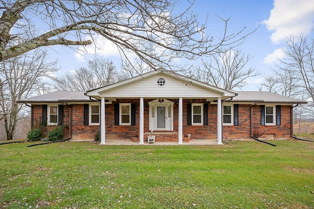 view of front of property featuring covered porch, metal roof, brick siding, and a front lawn