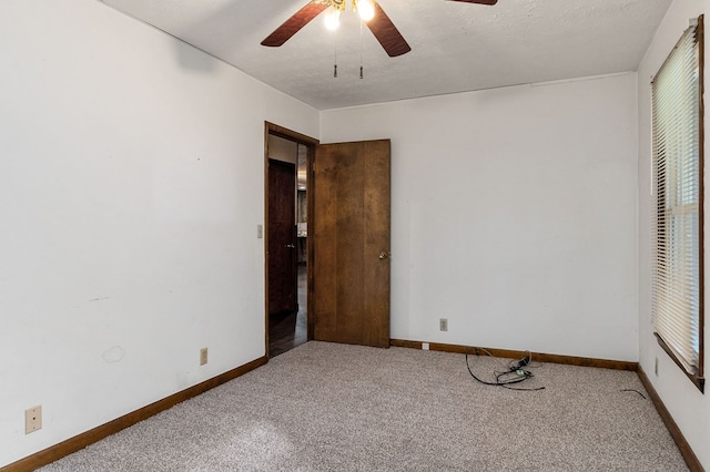 carpeted spare room featuring a textured ceiling, a ceiling fan, and baseboards