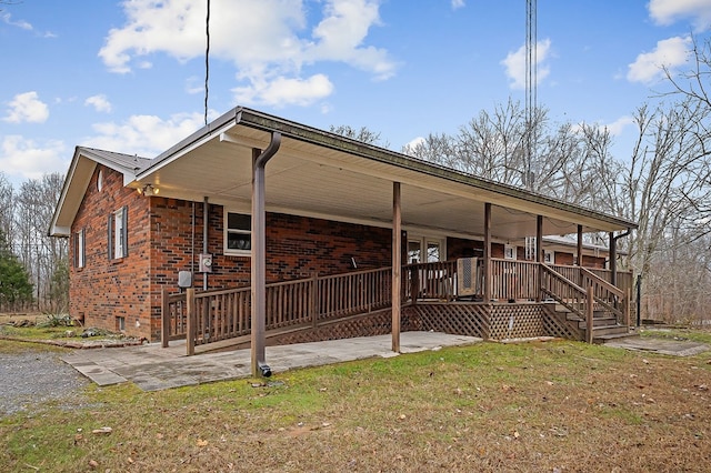 exterior space with a porch, a front yard, a patio area, and brick siding