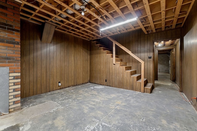 unfinished below grade area featuring wooden walls and stairs