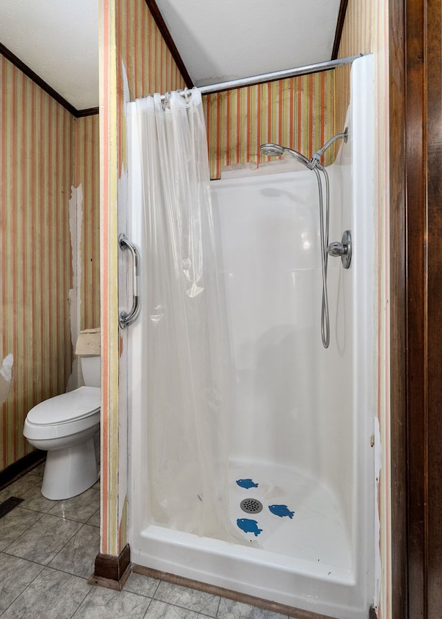 bathroom with wallpapered walls, toilet, ornamental molding, tile patterned floors, and a shower stall