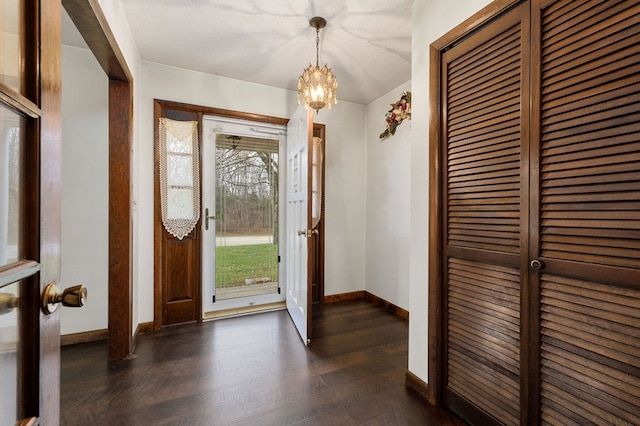 foyer entrance with baseboards, dark wood finished floors, and a notable chandelier