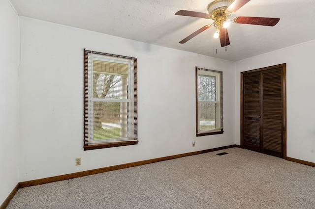 unfurnished bedroom with a textured ceiling, light carpet, visible vents, baseboards, and a closet