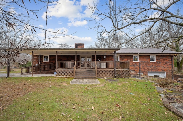 back of house featuring a yard, a chimney, a porch, and brick siding