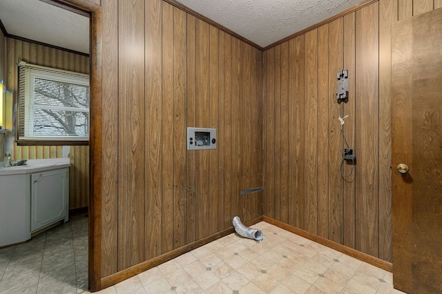 clothes washing area featuring light floors, hookup for a washing machine, cabinet space, wood walls, and a textured ceiling