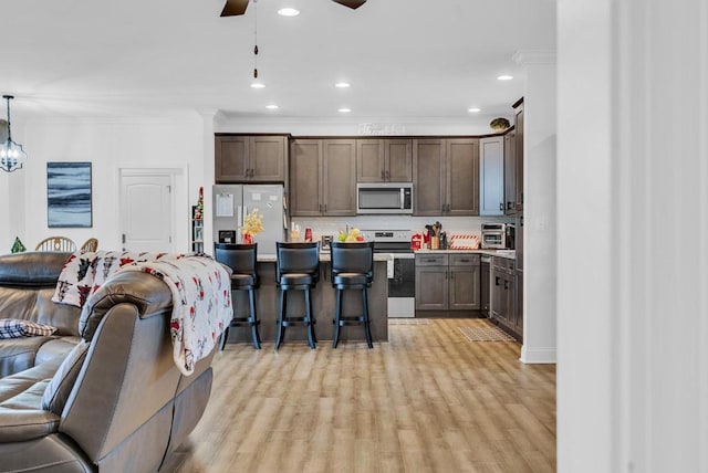 kitchen featuring stainless steel appliances, open floor plan, hanging light fixtures, light countertops, and tasteful backsplash