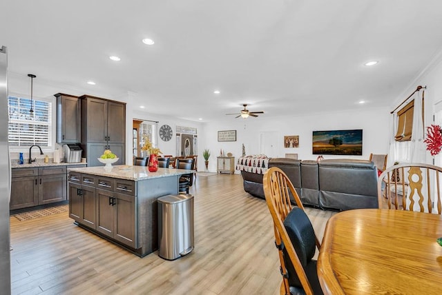 kitchen featuring light stone counters, open floor plan, decorative light fixtures, and light wood finished floors