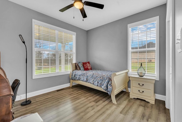 bedroom featuring multiple windows, light wood-type flooring, and baseboards