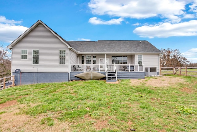 rear view of property featuring a deck, a lawn, and fence