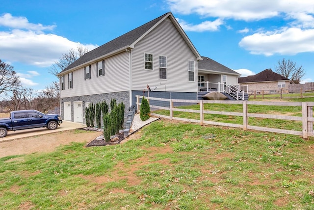 view of home's exterior featuring an attached garage, driveway, fence, and a yard