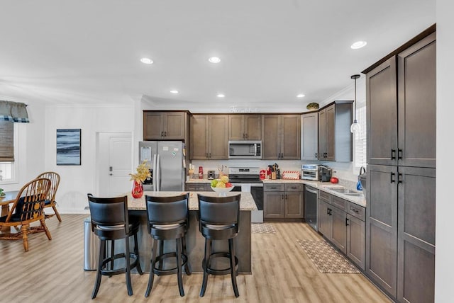 kitchen with pendant lighting, a breakfast bar area, stainless steel appliances, a kitchen island, and crown molding