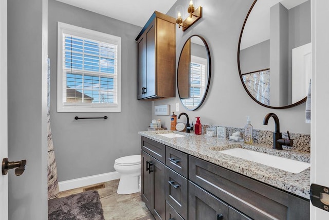 bathroom with toilet, a sink, visible vents, and baseboards