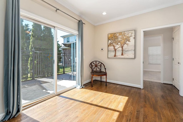 sitting room featuring plenty of natural light, baseboards, wood finished floors, and ornamental molding