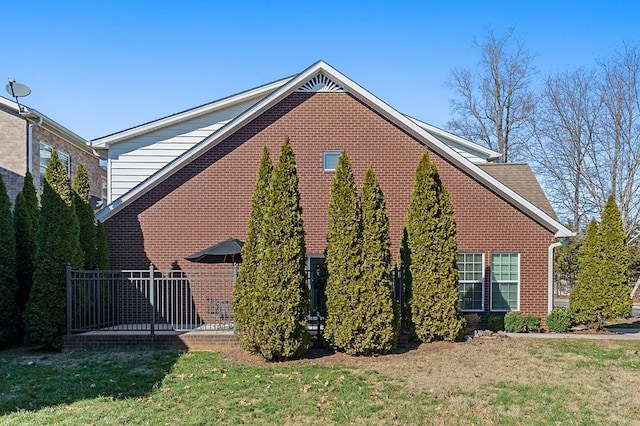 view of side of property with brick siding and a yard