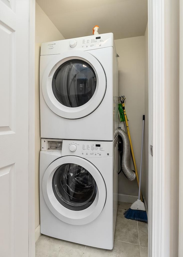 washroom with stacked washer and dryer, light tile patterned floors, and laundry area