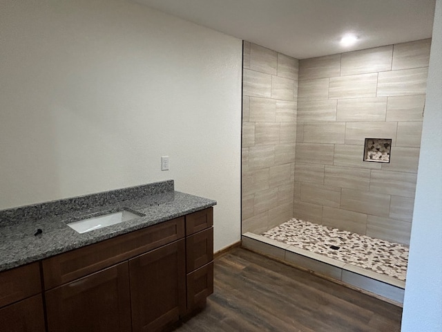 bathroom featuring tiled shower, a sink, and wood finished floors