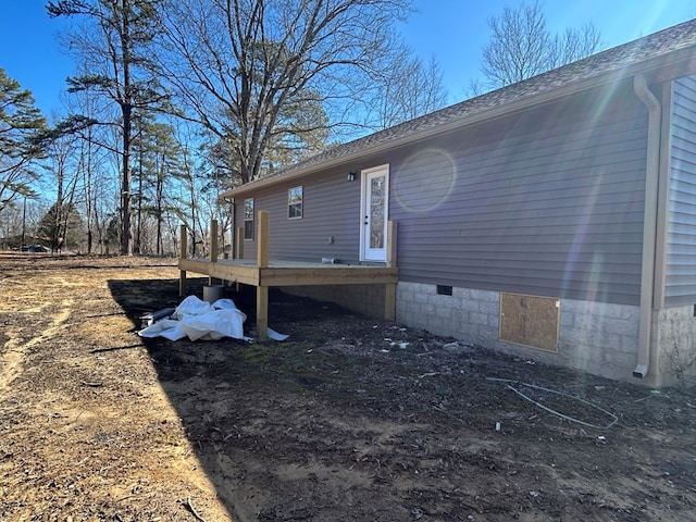 view of side of property with crawl space, roof with shingles, and a wooden deck