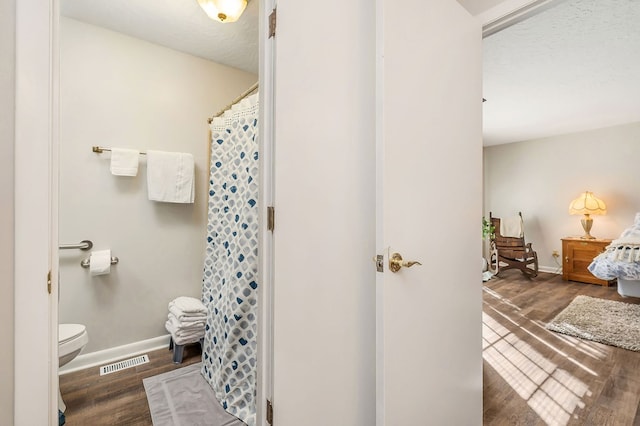 bathroom featuring toilet, baseboards, visible vents, and wood finished floors