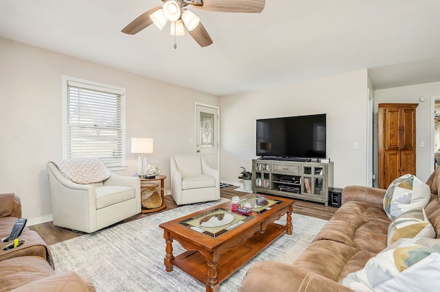 living area with wood finished floors, a ceiling fan, and baseboards