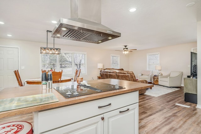 kitchen featuring light wood finished floors, a wealth of natural light, exhaust hood, open floor plan, and black electric cooktop