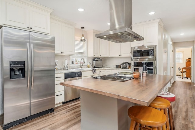 kitchen featuring a breakfast bar area, island range hood, stainless steel appliances, white cabinets, and light wood finished floors