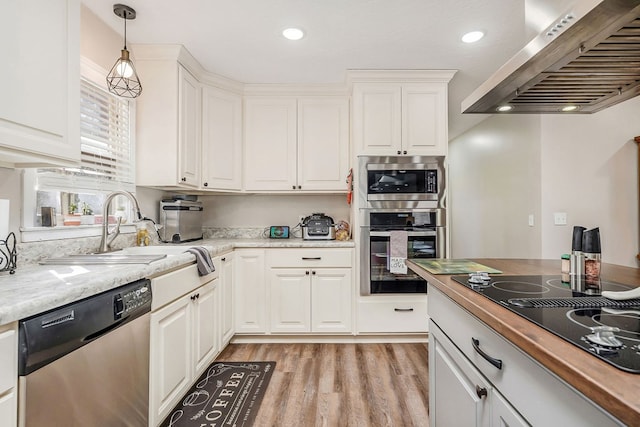 kitchen featuring hanging light fixtures, light wood-style flooring, appliances with stainless steel finishes, white cabinets, and extractor fan