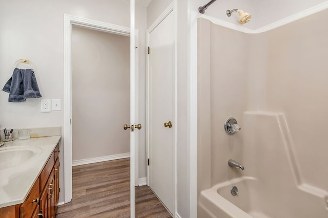 full bathroom featuring washtub / shower combination, baseboards, wood finished floors, and vanity