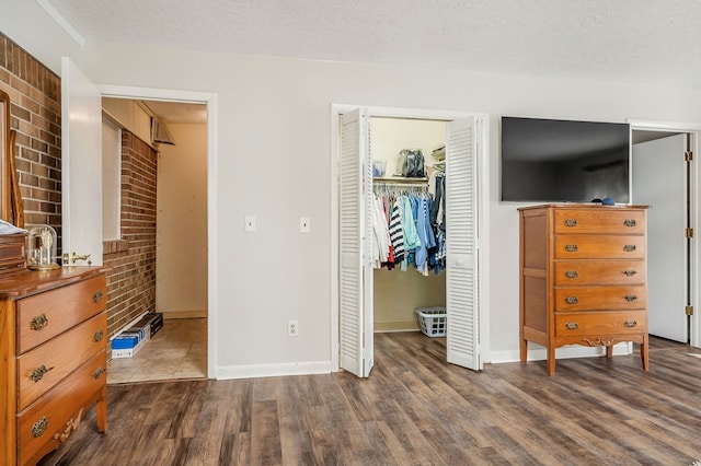 bedroom featuring a closet, dark wood-style flooring, a textured ceiling, and baseboards