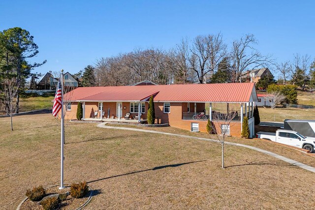 view of front of property with covered porch, brick siding, metal roof, and a front lawn