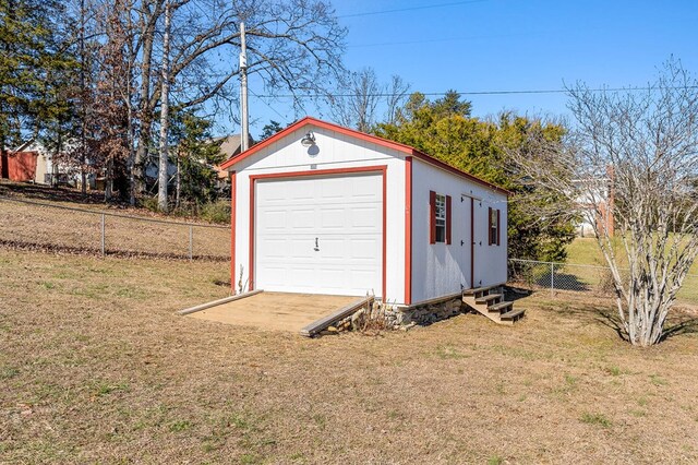 detached garage featuring fence and driveway