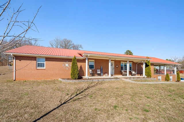 view of front of house with metal roof, brick siding, a porch, and a front yard