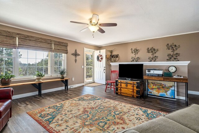 living room with ornamental molding, dark wood-style flooring, ceiling fan, and baseboards