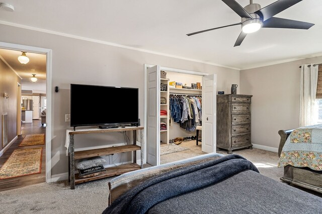 bedroom featuring baseboards, a spacious closet, ornamental molding, and light colored carpet