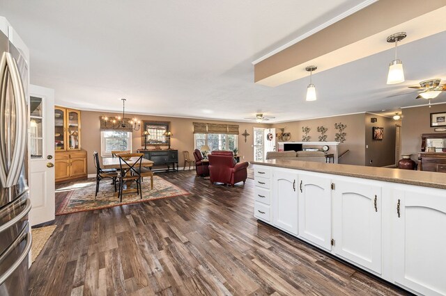 kitchen with stainless steel fridge, pendant lighting, white cabinetry, and open floor plan