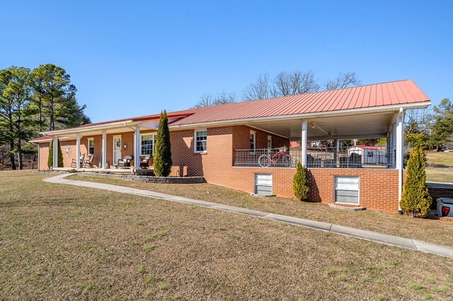 view of front of home with metal roof, a front yard, a porch, and brick siding