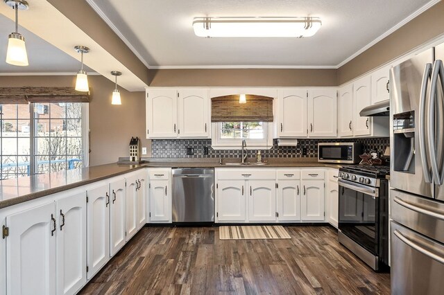 kitchen with white cabinets, stainless steel appliances, and decorative light fixtures