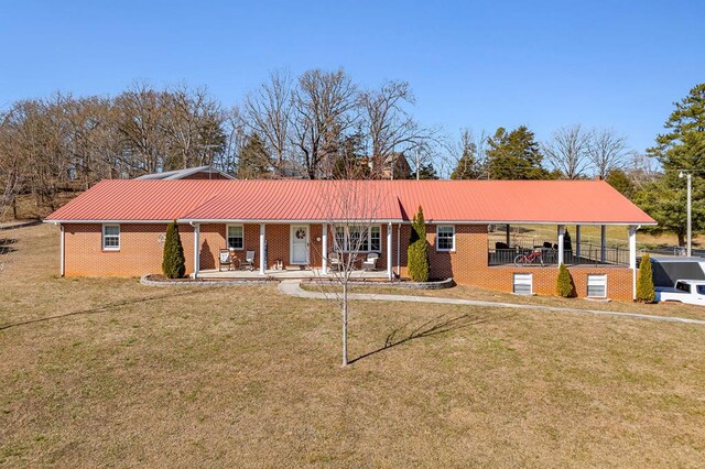 ranch-style house featuring covered porch, a front yard, metal roof, and brick siding