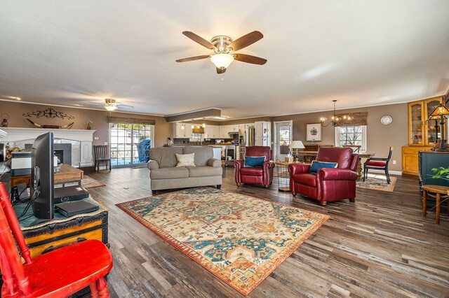 living room with dark wood-type flooring, baseboards, and ceiling fan with notable chandelier