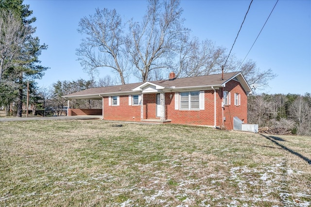 single story home featuring an attached carport, a chimney, a front yard, and brick siding