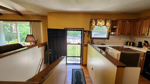 kitchen featuring open shelves, dark countertops, brown cabinetry, light wood-style floors, and a textured ceiling