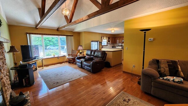 living area featuring lofted ceiling with beams, light wood-style floors, and baseboards