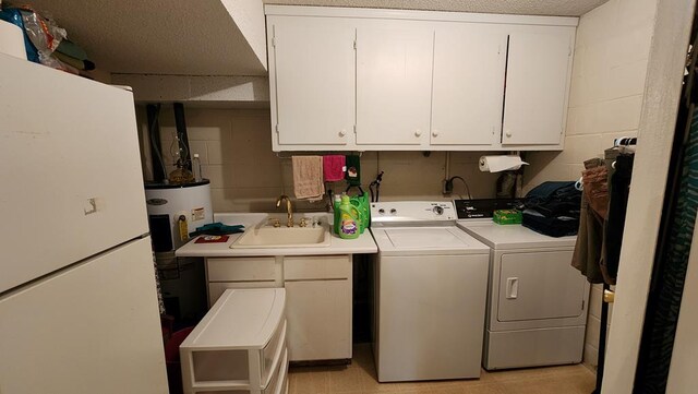 washroom with concrete block wall, cabinet space, independent washer and dryer, a textured ceiling, and a sink