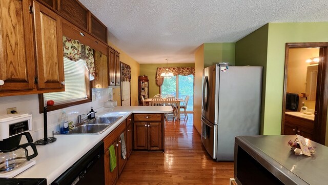 kitchen featuring a sink, light countertops, decorative light fixtures, and freestanding refrigerator