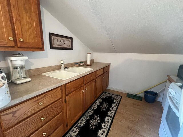 interior space featuring a sink, light countertops, light wood-type flooring, white stove, and brown cabinetry